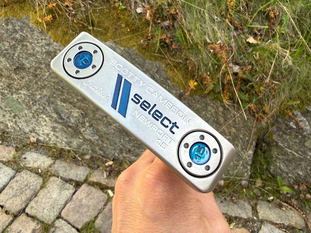 Close-up of a silver Scotty Cameron Select Newport golf putter being held outdoors.